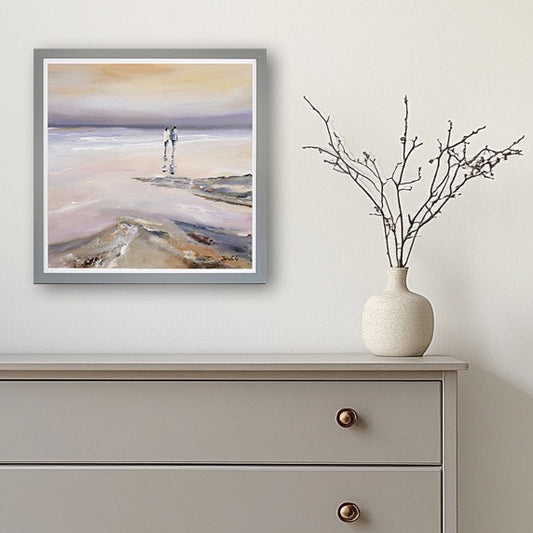 Framed artwork on a wall above a dresser with a vase containing branches.