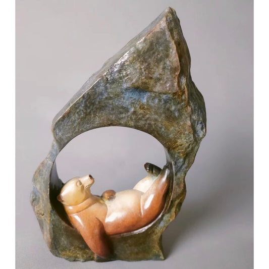 Bronze sculpture of a bear inside a rock on a gray background