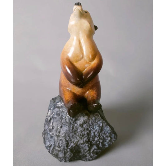 Bronze Bear sculpture on a rock against a gray background