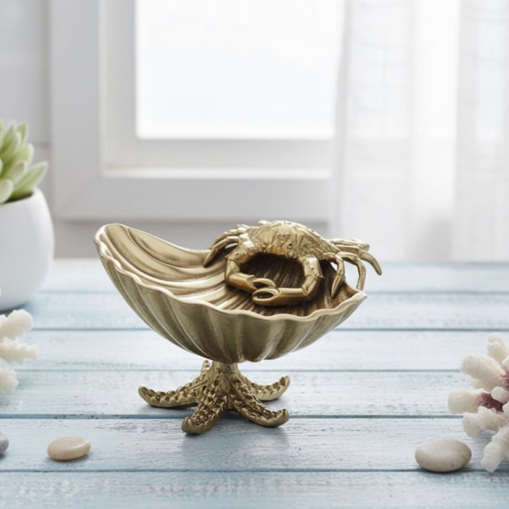 Gold crab figurine inside a shell on a wooden surface with a light background