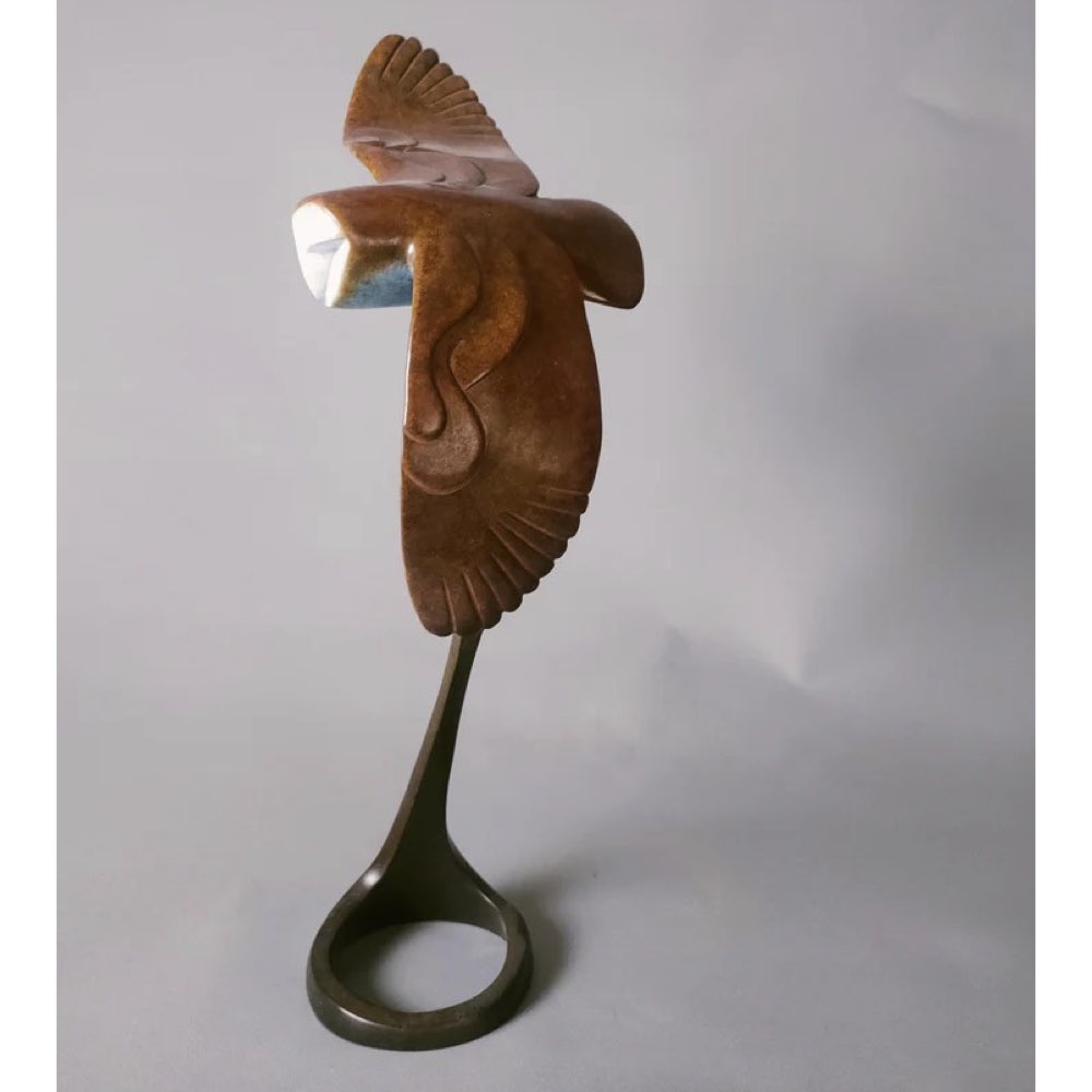Bronze sculpture of a bird on a stand against a plain background