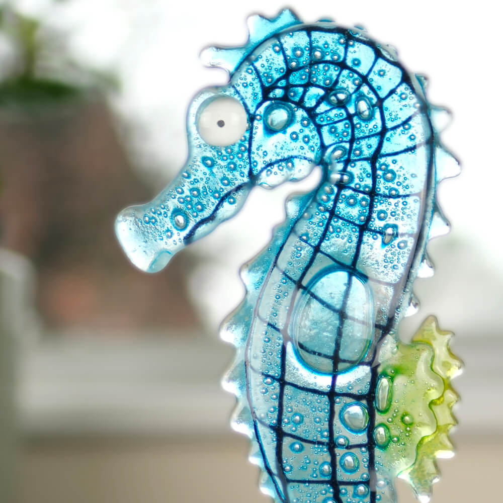 Decorative glass seahorse with bubble design on a blurred background