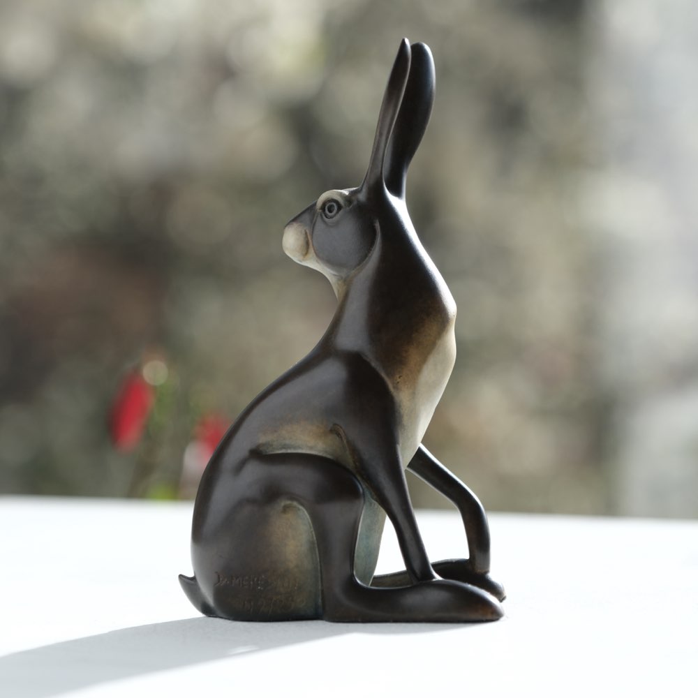 Bronze sculpture of a hare on a blurred natural background