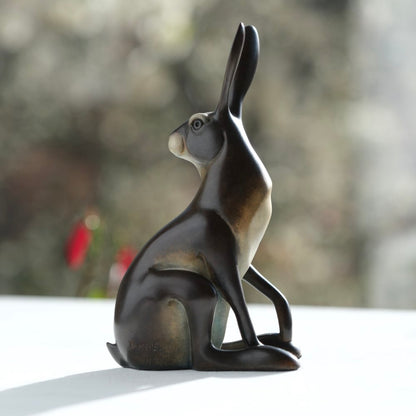 Bronze sculpture of a hare on a blurred natural background