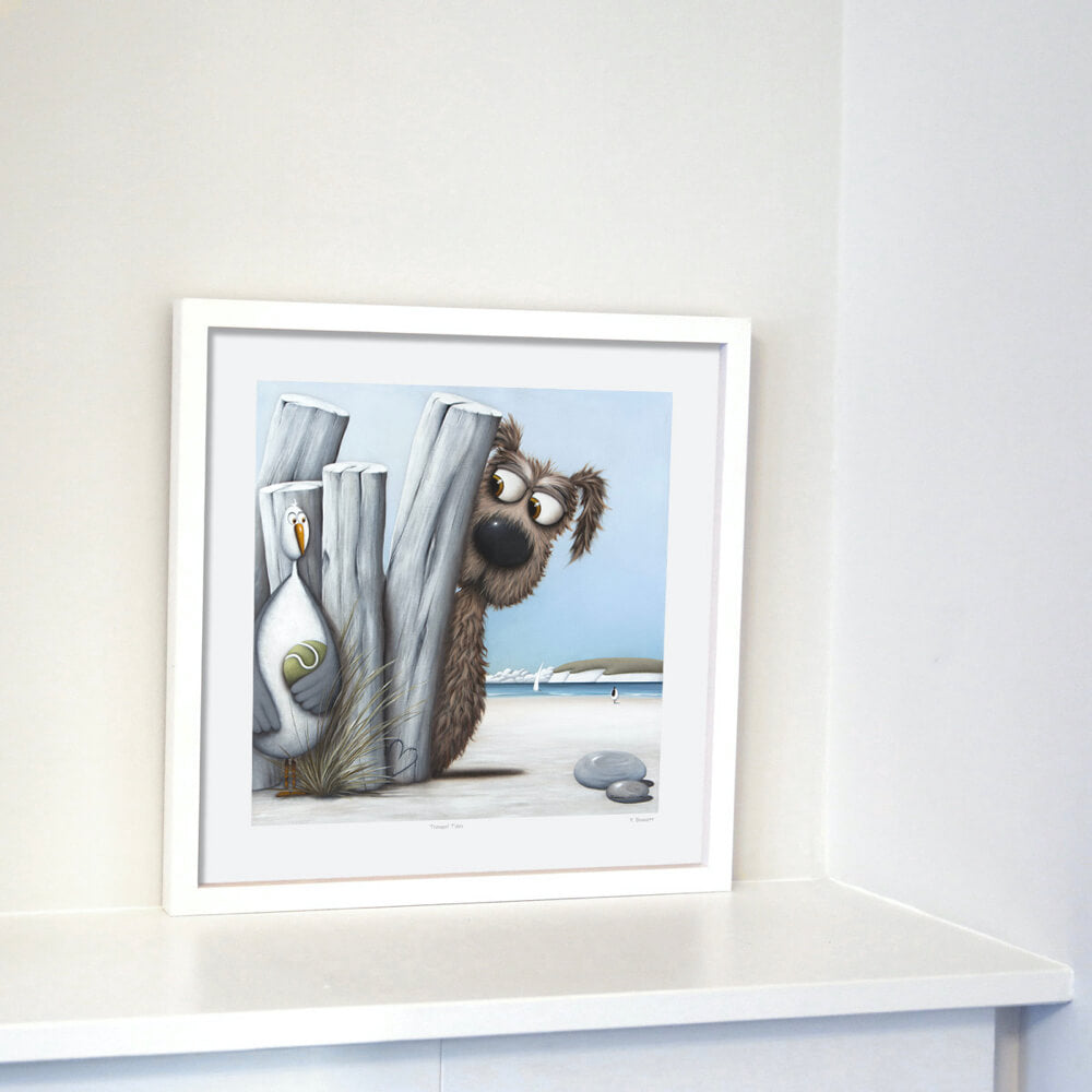 A framed print featuring a whimsical illustration of a dog holding a tennis racket, with a ball in the background. The frame is white, and the artwork is displayed on a white surface against a neutral wall.