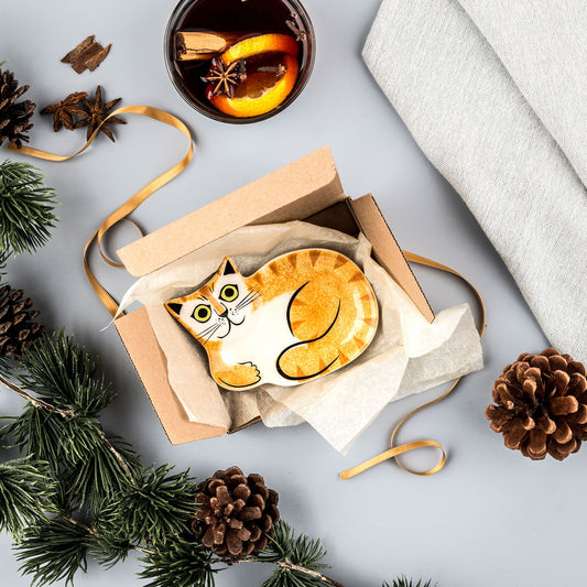 Cat-shaped soap in a box with a cup of tea and decorative elements on a light gray background