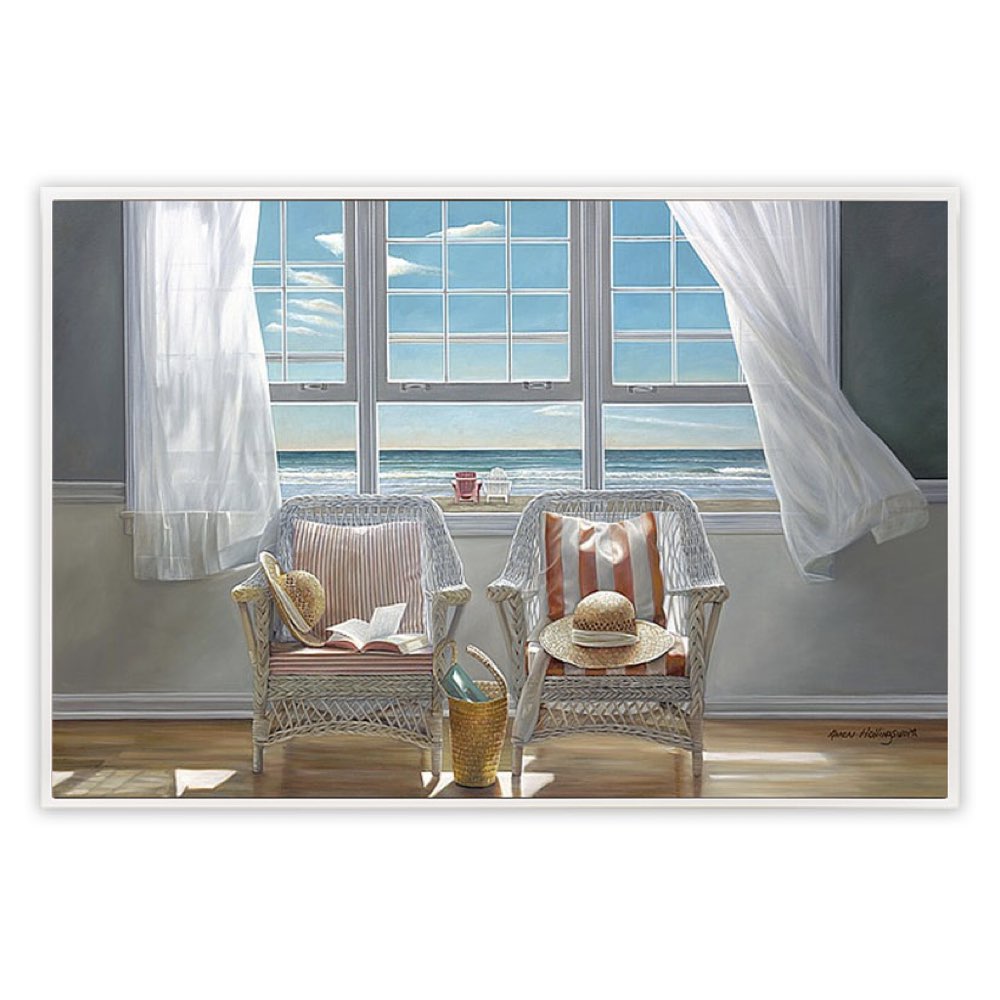 Two wicker chairs with cushions by a large window with white curtains, overlooking a blue sky.