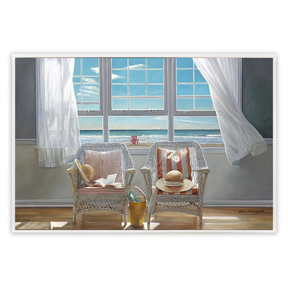 Two wicker chairs with cushions by a large window with white curtains, overlooking a blue sky.