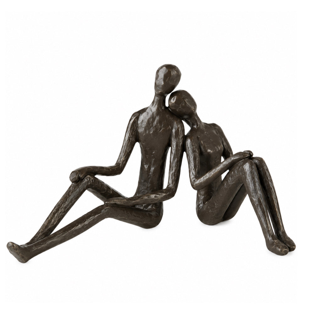A dark bronze sculpture of a seated couple embracing, shown against a plain white background.