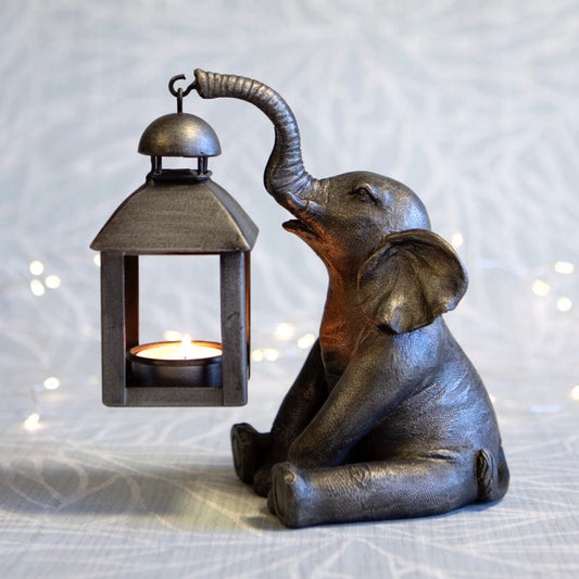 Decorative elephant holding a lantern with a soft light on a textured surface.