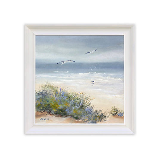 Framed artwork of a beach scene with seagulls and vegetation.