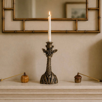 A giraffe-shaped candlestick holder with a lit white taper candle, displayed on a mantelpiece below a mirror.