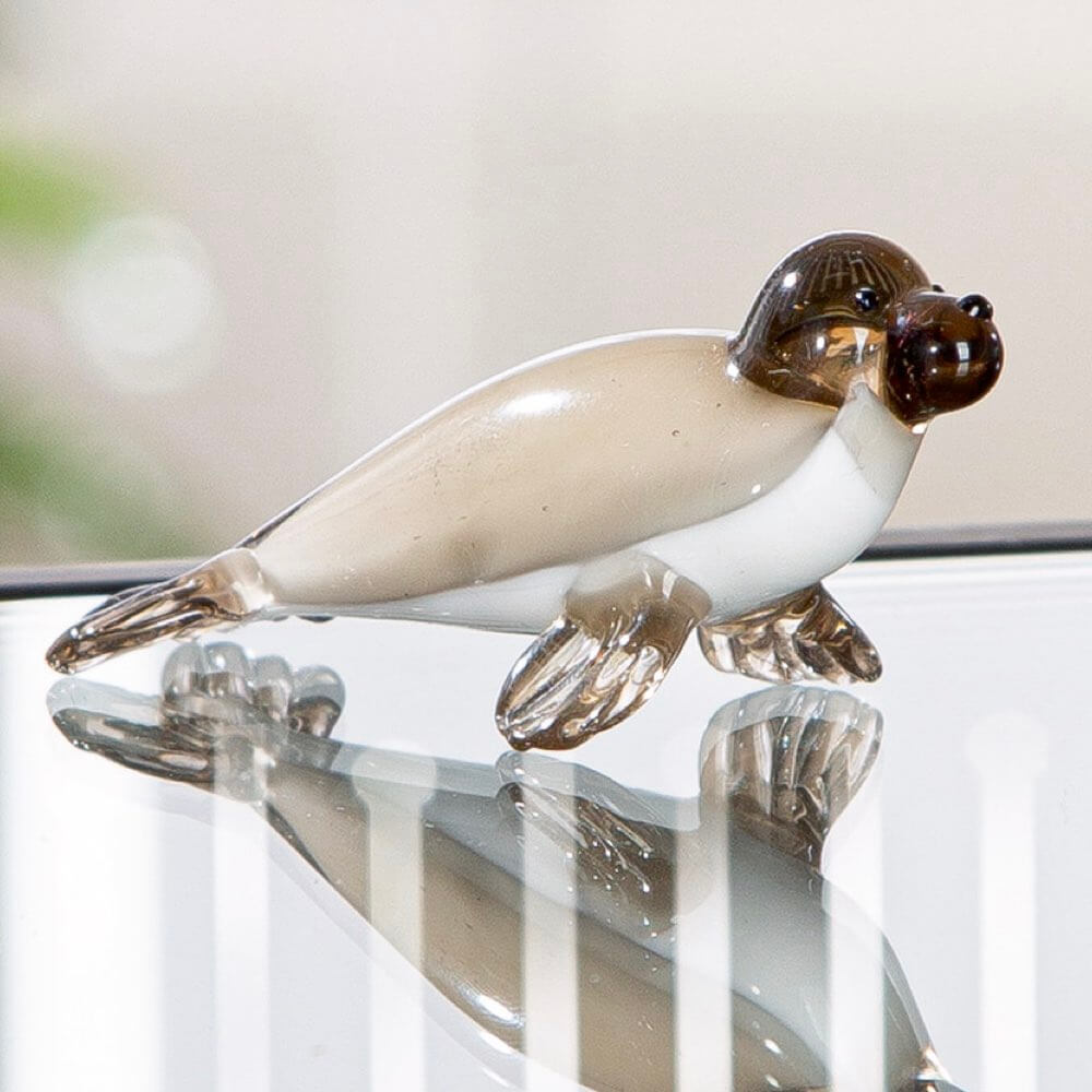 Glass seal figurine on a reflective surface with a blurred background
