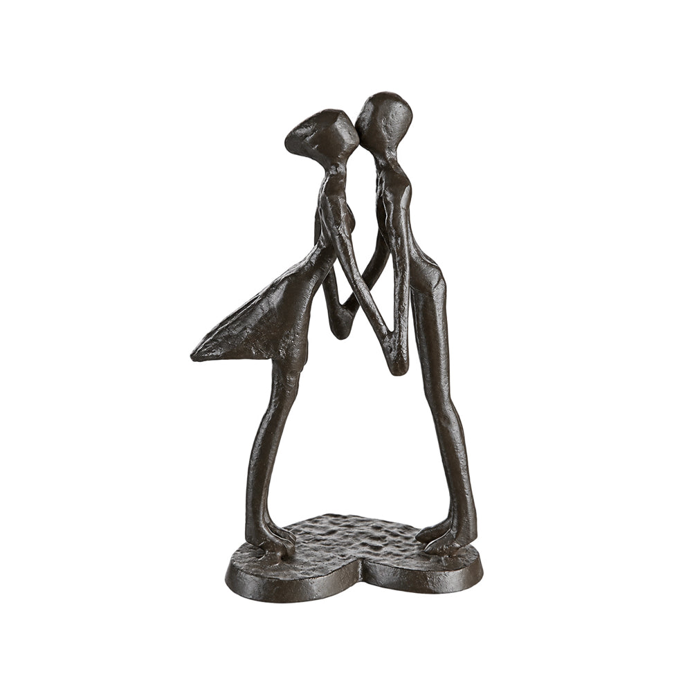 A dark bronze sculpture of two abstract, elongated human figures embracing and leaning toward each other, mounted on a textured heart-shaped base against a plain white background.