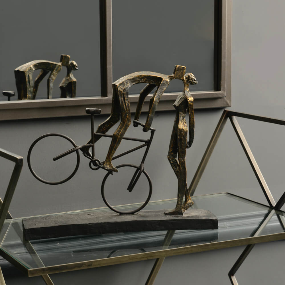 Bronze sculpture of a cyclist on a bike embracing their partner 