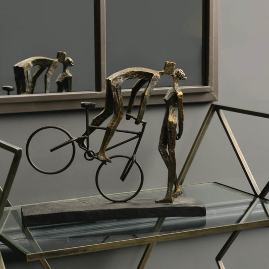 Bronze sculpture of a cyclist on a bike embracing their partner 
