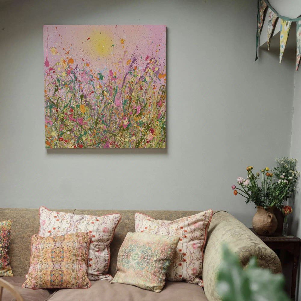Floral painting on a wall above a sofa with patterned cushions.