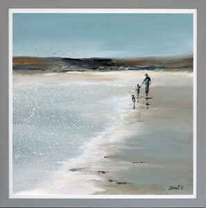 Two people walking on a beach with a lighthouse in the distance.