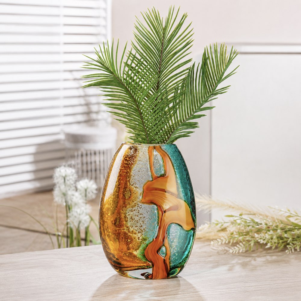 Decorative vase with abstract design and green palm leaves on a light surface.