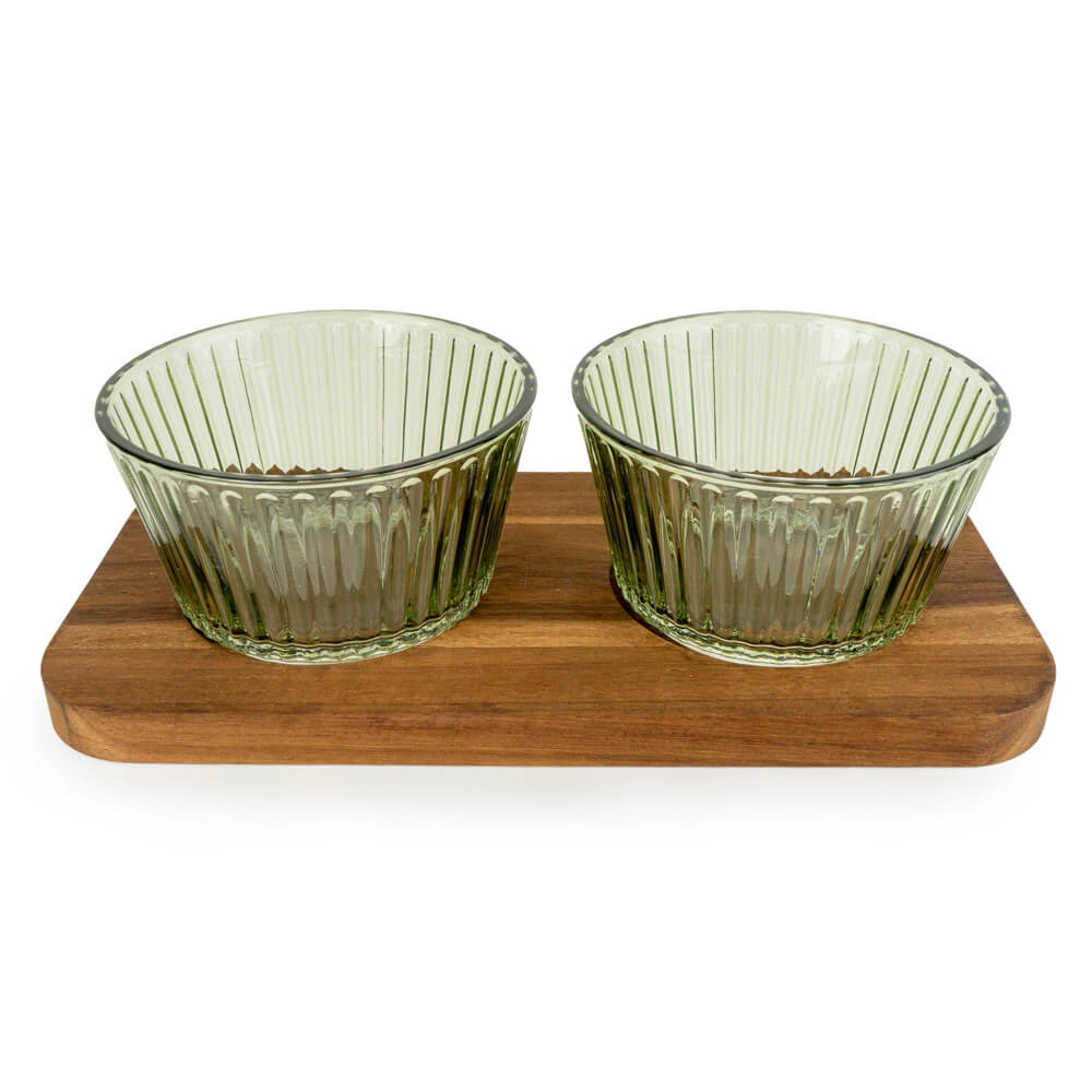 Two green glass bowls on a wooden tray with a white background
