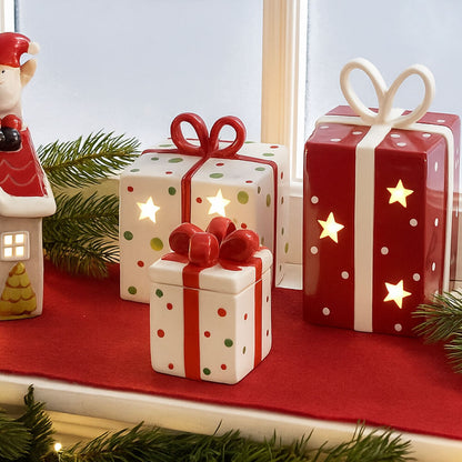 Decorative Christmas gift boxes with candles on a red surface