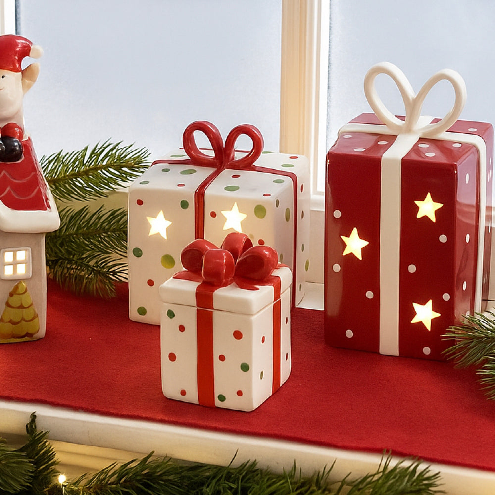 Decorative ceramic gift boxes with LED lights on a red surface.