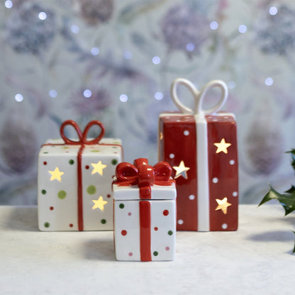 Three decorative gift boxes with ribbons and star accents on a blurred floral background