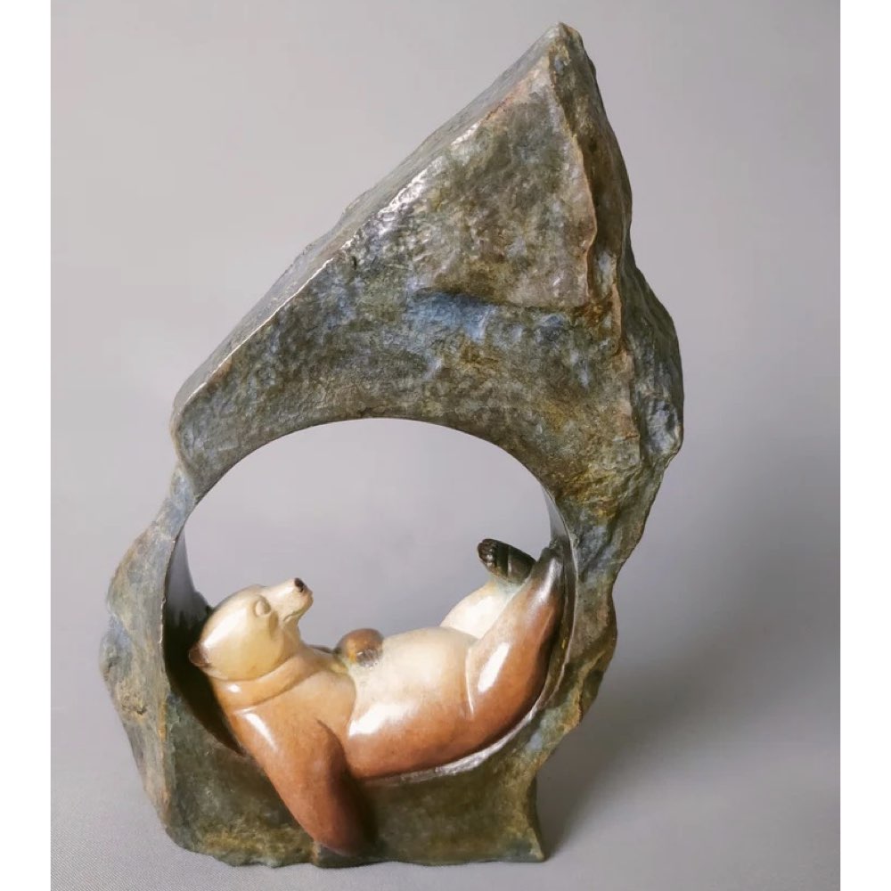 Bronze sculpture of a bear inside a rock on a gray background
