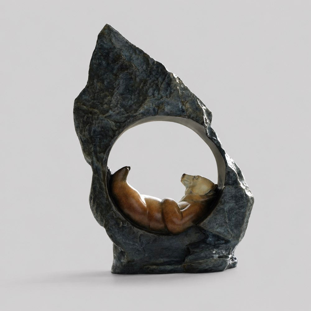 Bronze sculpture of a bear asleep and dreaming in its favourite rock.