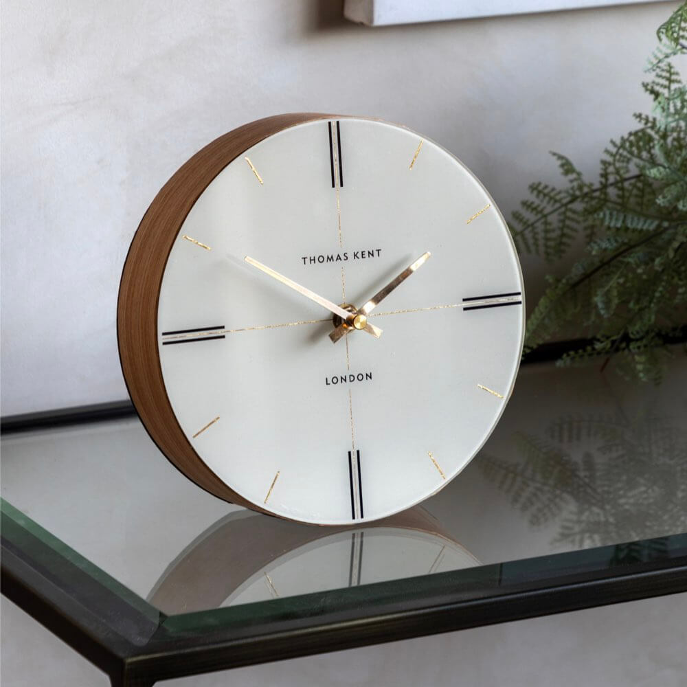 Round clock with wooden rim on a reflective surface, featuring the brand 'Thomas Kent'.