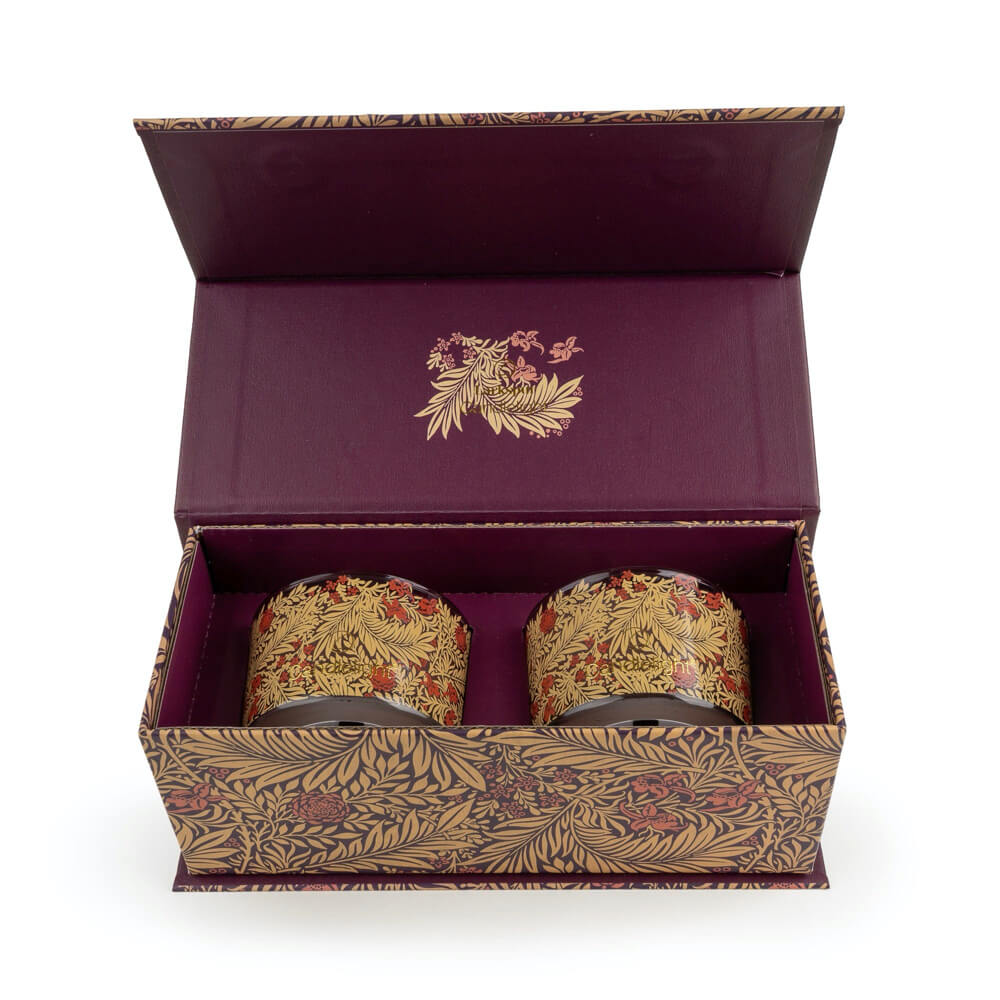 Two ornate candles in a decorative box with floral patterns on a white background