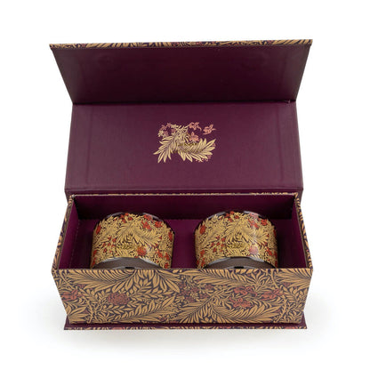 Two ornate candles in a decorative box with floral patterns on a white background