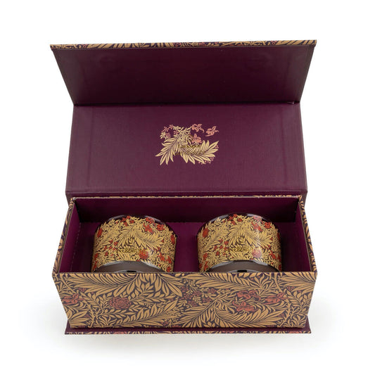 Two ornate candles in a decorative box with floral patterns on a white background