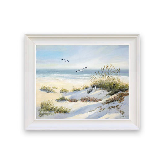 Framed artwork of a beach scene with sand, grass, and birds.
