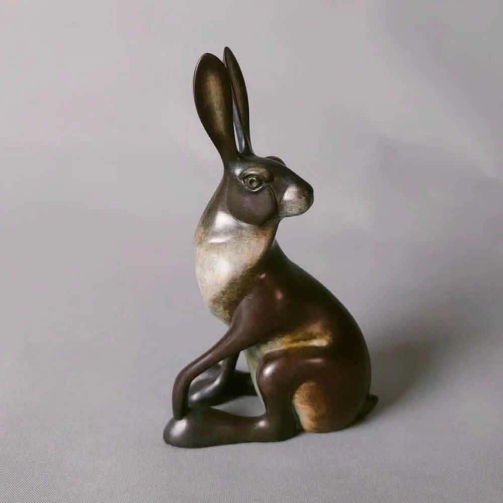 Bronze sculpture of a hare on a gray background