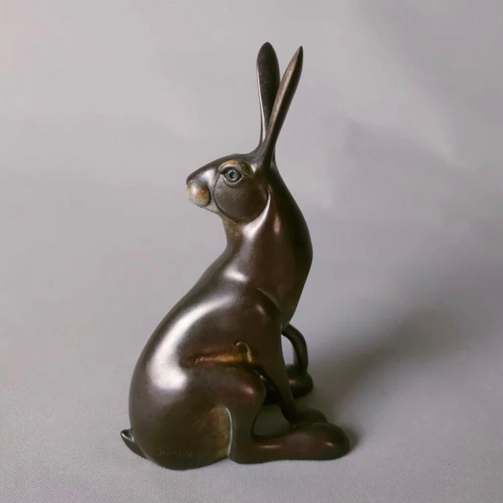 Bronze hare sculpture on a light gray background