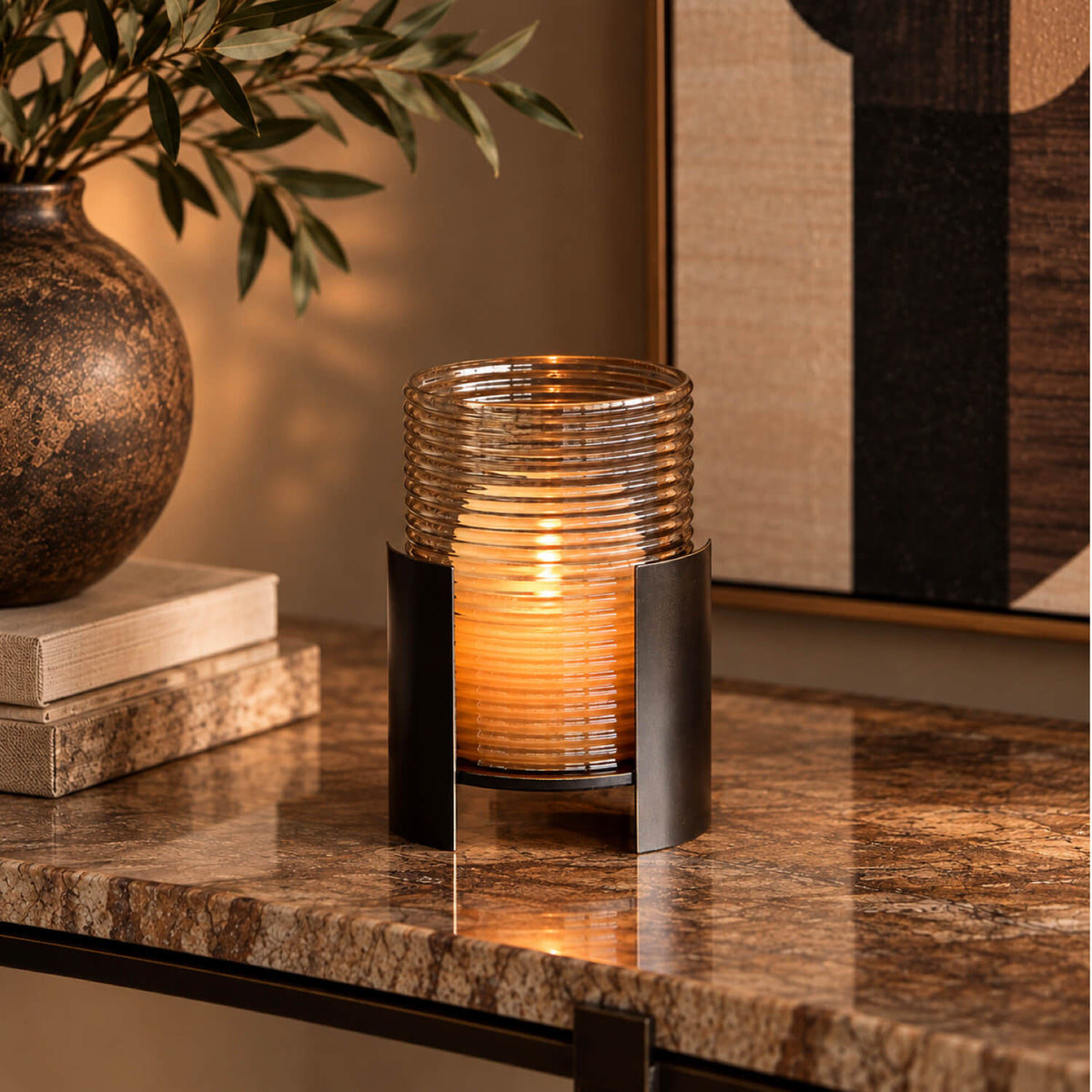 Smoked Gold Hurricane Small on a marble console, featuring ribbed smoked gold glass and a dark bronze frame with a lit candle inside.