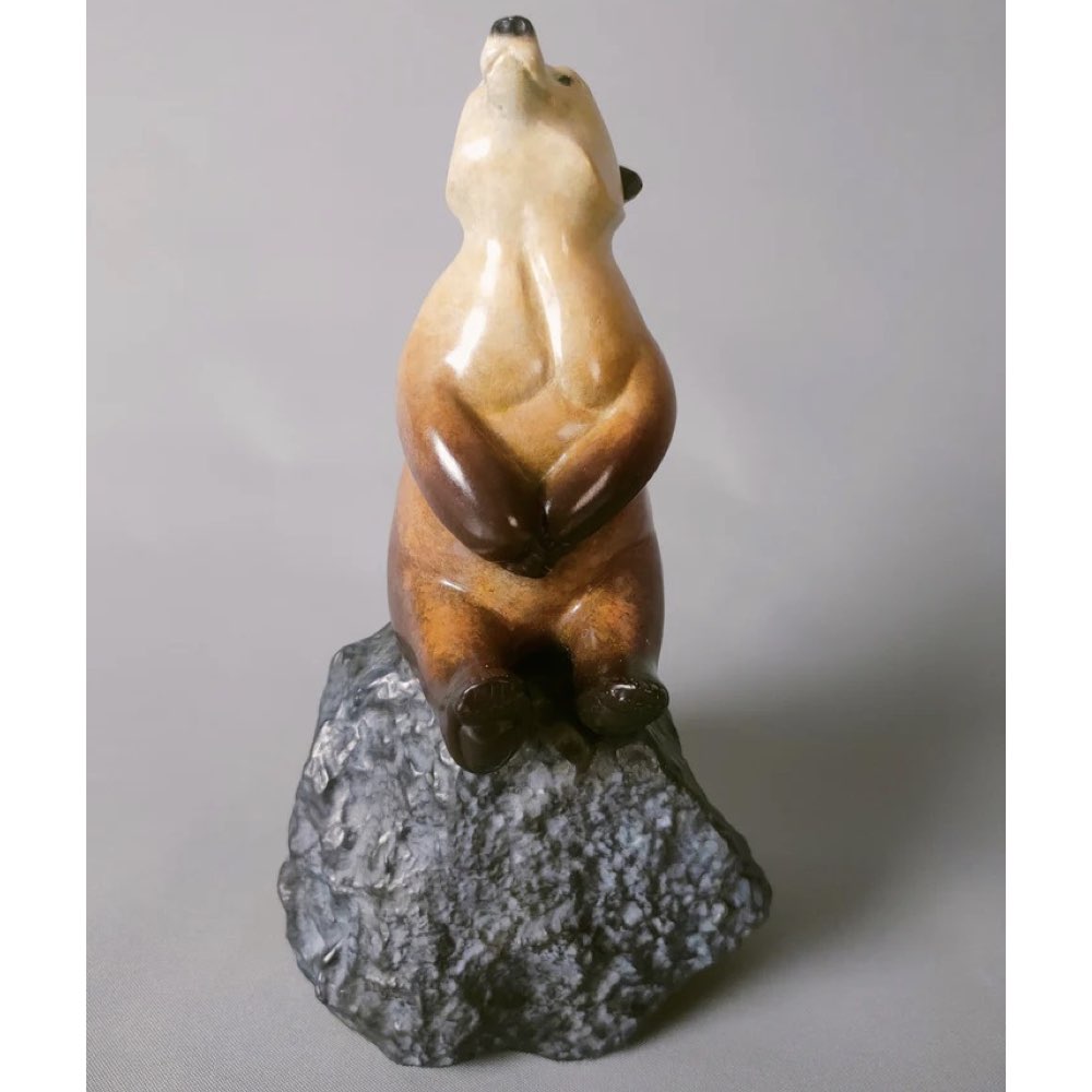 Bronze Bear sculpture on a rock against a gray background