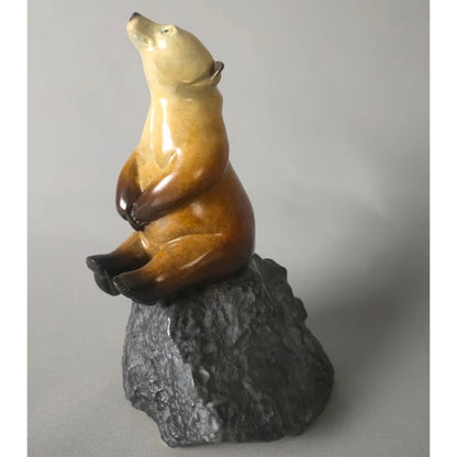 Bronze star gazing bear sculpture on a rock against a gray background