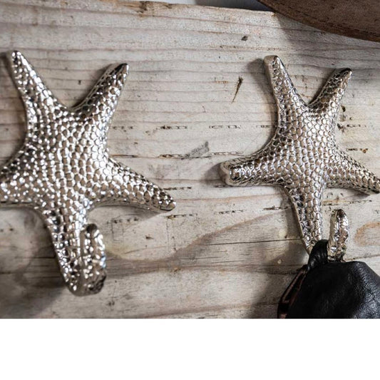 Two metallic starfish wall decorations on a wooden surface.