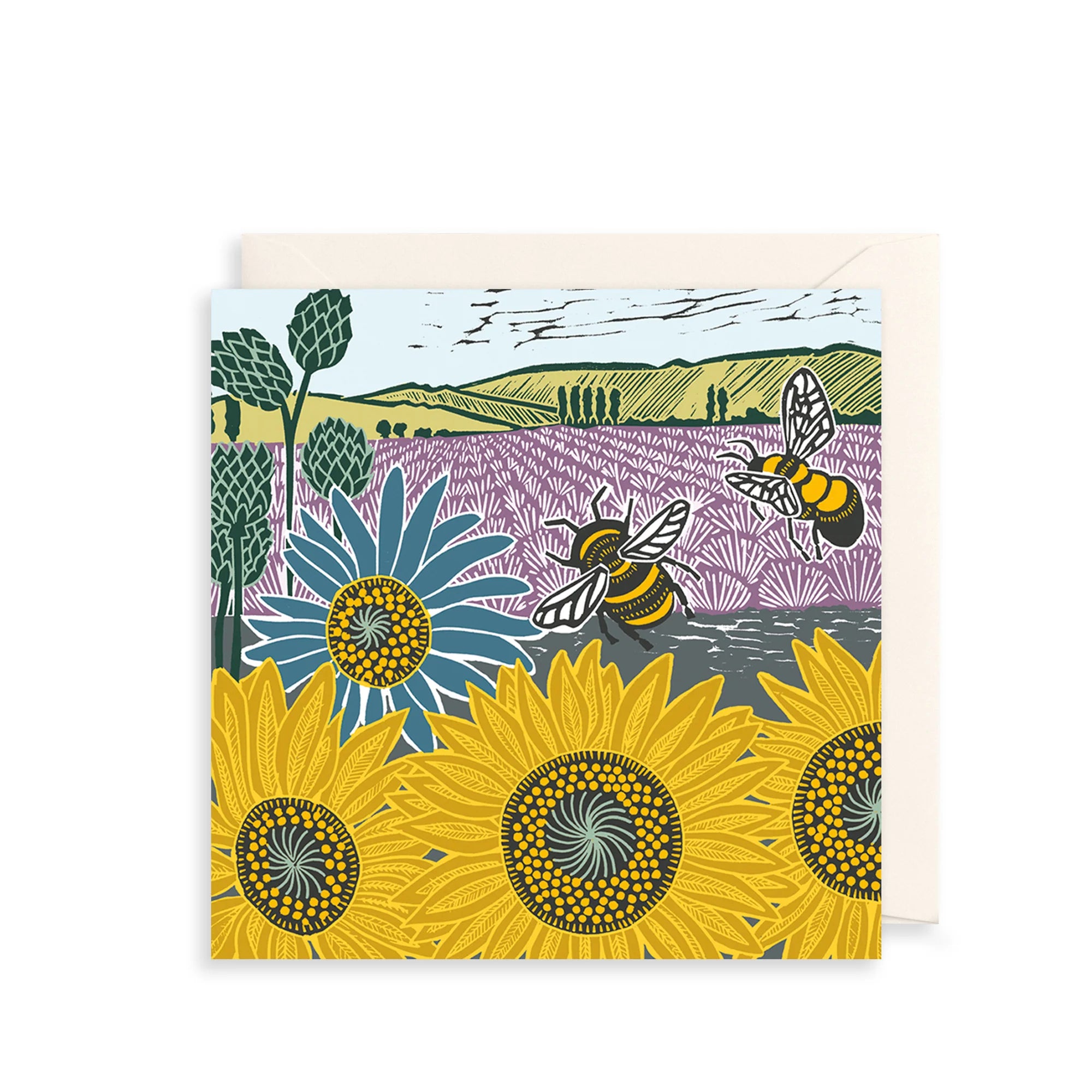 A square art print or card featuring a stylized landscape with sunflowers, a lavender field, trees, and two bees, shown with a cream envelope behind it on a white background.