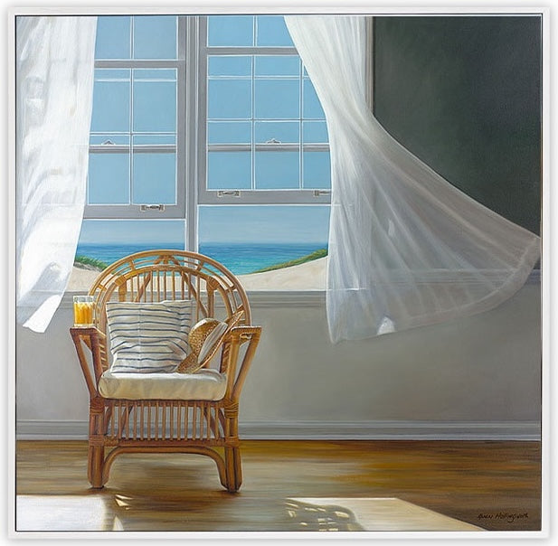 Wicker chair with cushions in front of a large window with white curtains, showing a beach view.