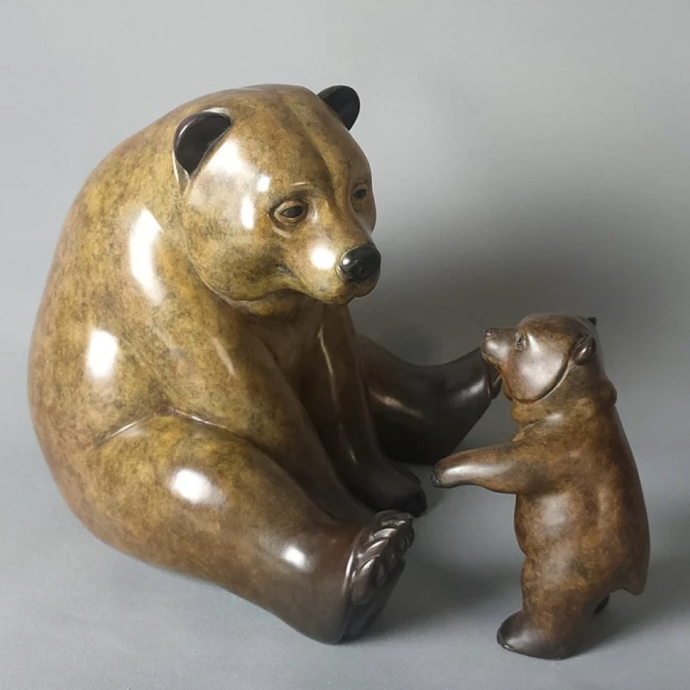 Bronze sculpture of a bear and a cub on a gray background
