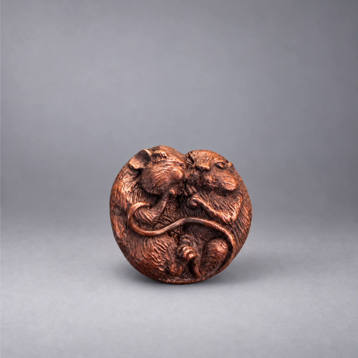 Close-up of two bronze mice curled together, showing their textured fur, tiny paws and intertwined tails, by David Meredith.