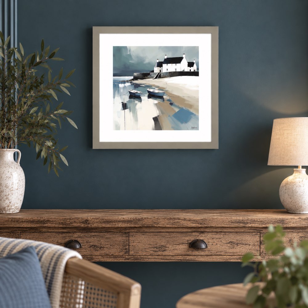A framed art print depicting a coastal scene with boats and a white building, displayed on a dark teal wall above a rustic wooden console table with a lamp and vase.