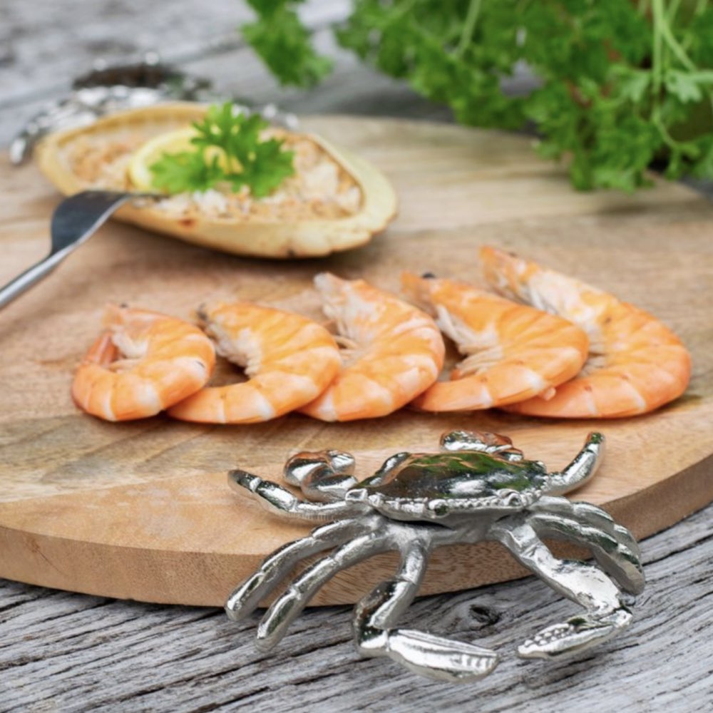 Shrimp on a wooden board with a crab-shaped handle in the foreground.