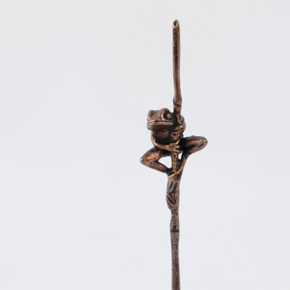 Bonsai bronze frog perched on a grass stem 