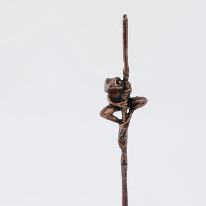 Bonsai bronze frog perched on a grass stem 