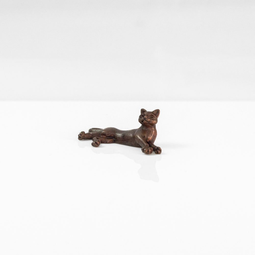 A small bronze figurine of a lying cat. 